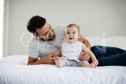 Father playing with his baby girl in bedroom