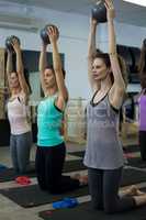 Fit women performing stretching exercise with fitness ball in gym