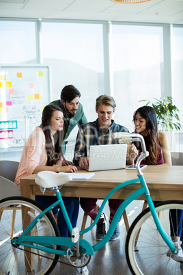 Smiling creative business team discussing over laptop