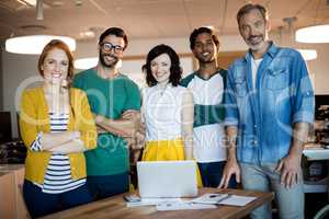 Portrait of smiling creative business team standing at the desk with laptop
