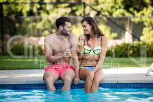 Young couple having iced tea at poolside