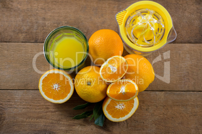 Overhead of oranges with glasses of juice and juicer