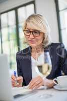 Businesswoman writing on diary in a restaurant