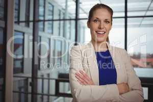 Portrait of beautiful businesswoman standing with arms crossed in corridor