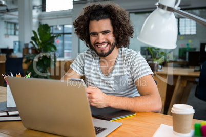 Smiling graphic designer using mobile phone in creative office