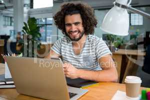 Smiling graphic designer using mobile phone in creative office