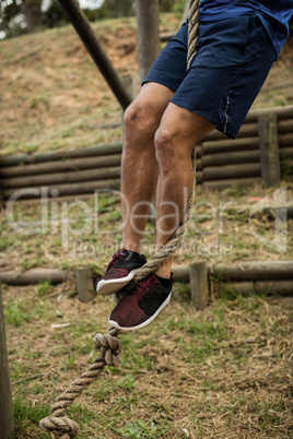 Low section of man climbing a rope during obstacle course