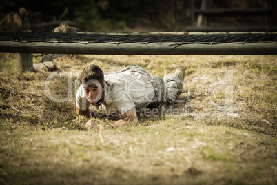 Soldier crawling under the net during obstacle course