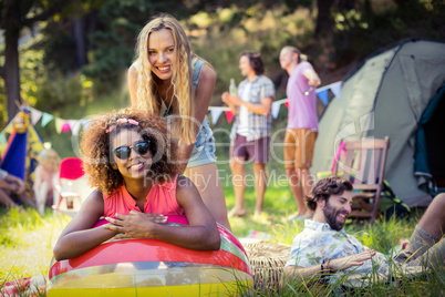 Portrait of friends leaning on beach ball at campsite