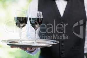 Male waiter holding tray with wine glasses