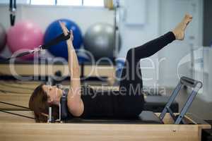 Woman practicing stretching exercise on reformer