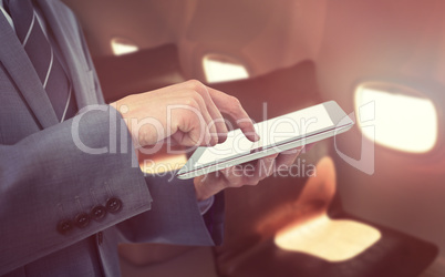 Composite image of midsection of businessman using tablet computer