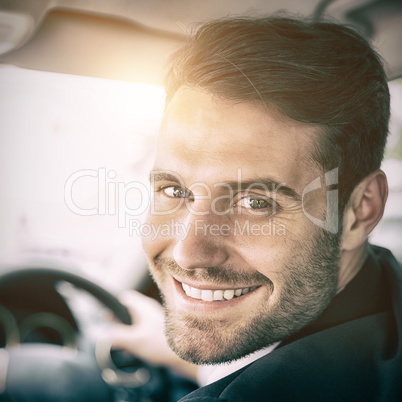 Man sitting in a car and holding a smartphone smiling at camera