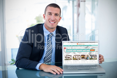 Composite image of portrait of smiling businessman showing laptop