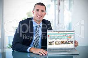 Composite image of portrait of smiling businessman showing laptop