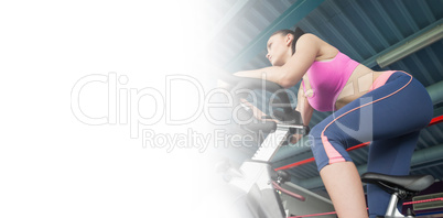 Determined young woman working out at spinning class