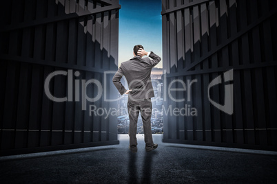 Composite image of young businessman standing back to camera scratching his head 3d