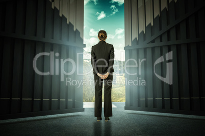 Composite image of businesswoman standing with hands behind back 3d
