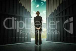 Composite image of businesswoman standing with hands behind back 3d