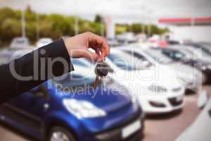 Composite image of couple receiving car keys by a dealer