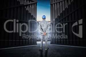 Composite image of businessman with helmet turning his back to camera 3d