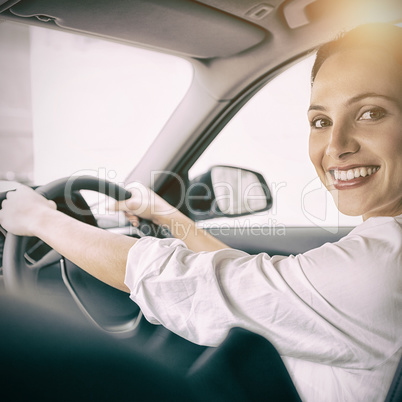 Woman holding steering wheel and smiling at camera