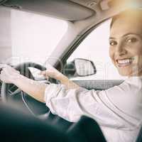 Woman holding steering wheel and smiling at camera