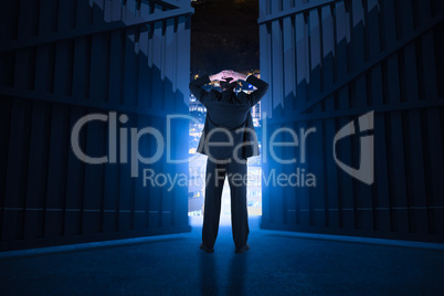 Composite image of businessman standing back to the camera with hands on head 3d