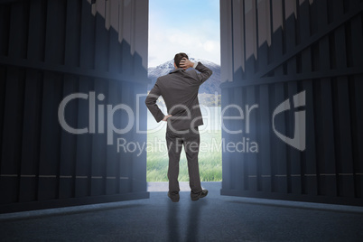 Composite image of young businessman standing back to camera scratching his head 3d
