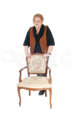 Senior woman standing on armchair.