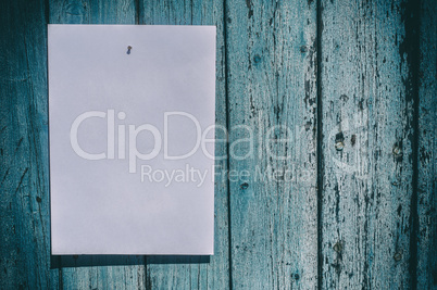 white sheet of paper hangs on a blue wooden wall