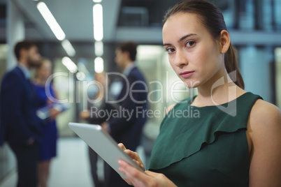 Female executive using digital tablet in corridor