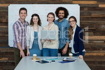 Portrait of smiling business team using laptop