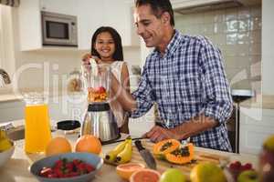 Father and daughter preparing smoothie in kitchen