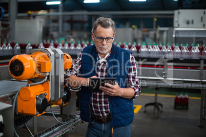 Factory worker using digital tablet next to production line