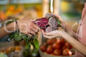 Vendor giving beetroot to the woman at the grocery store