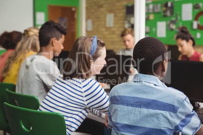 Rear view of students studying in computer classroom