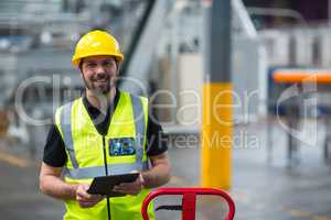 Portrait of smiling factory worker using a digital tablet