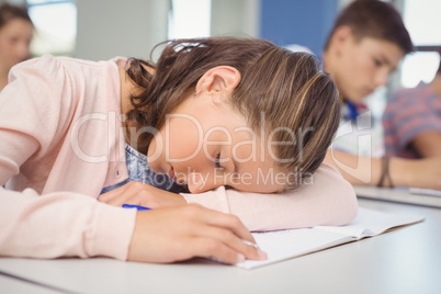 Tired schoolgirl sleeping in classroom