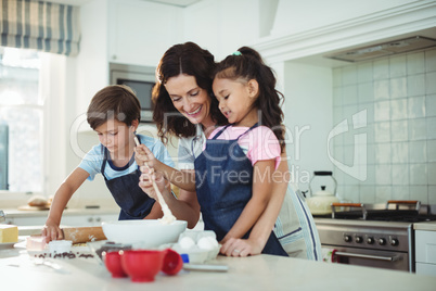 Mother and kids mixing the dough while preparing cookies