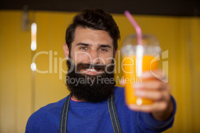 Male staff holding orange juice glass at organic section