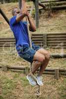 Fit man climbing a rope during obstacle course