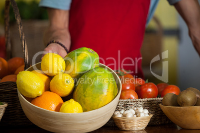 Staff holding a bowl of fruits at counter in market