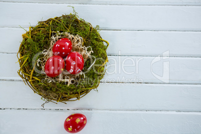 Red Easter eggs in the nest on wooden surface