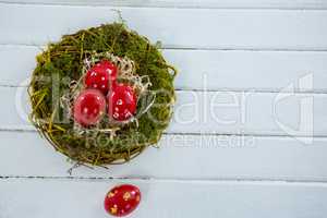 Red Easter eggs in the nest on wooden surface