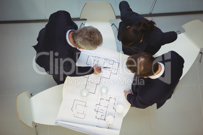 High angle view of businesspeople discussing over blueprint