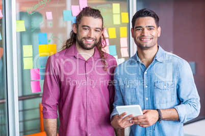 Smiling executives using digital tablet in office