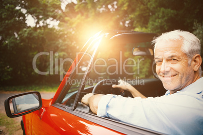 Smiling man driving red car