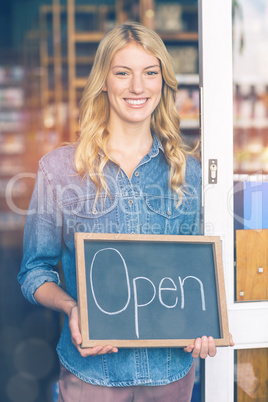Smiling owner holding open signboard in supermarket