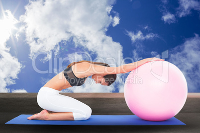 Composite image of side view of a fit woman exercising with fitness ball